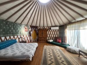 a bedroom with a tent with a bed and a rug at Meek Yurt in Yodefat