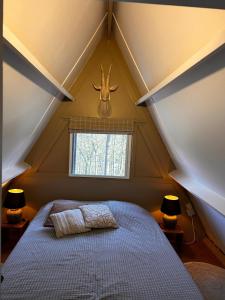 ein Dachgeschosszimmer mit einem Bett, an dessen Wand ein Hirschkopf hängt. in der Unterkunft Chalet Woods in Durbuy + 59 Fotos