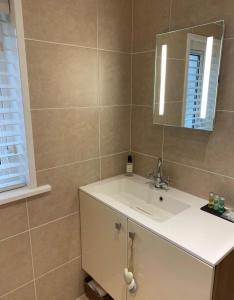 a bathroom with a white sink and a mirror at Heatherlea Cottage in Skigersta