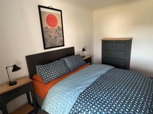 a bedroom with a blue and orange bed and a dresser at Heatherlea Cottage in Skigersta