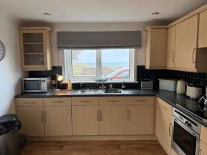 a kitchen with a sink and a window at Heatherlea Cottage in Skigersta