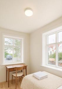 a bedroom with a bed and a desk and two windows at Downtown Boutique Apartment in Akureyri +5 photos