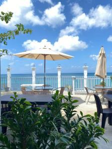 a patio with a table and an umbrella and the ocean at Beachfront Sunset Getaway in Allen