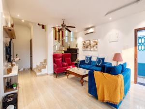 a living room with a blue couch and red chairs at DanCenter Infinity Villa I 5BHK I Pvt Pool I Baga I GOA in Goa