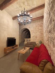 a living room with a couch and a chandelier at Serenity Wellness Farmhouse With Private Sauna in Nadur