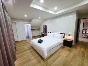 a bedroom with a large white bed and wooden floors at M-Well House in Sathani Ban Hua Mak