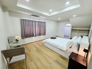a bedroom with a white bed and a table and a window at M-Well House in Sathani Ban Hua Mak +15 photos