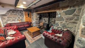 a living room with leather couches and a stone fireplace at Polbarrow in Ruan Minor