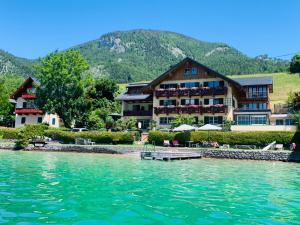 a hotel on the water in front of a mountain at Hotel Garni Buchinger in St. Wolfgang