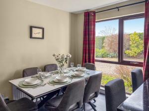 a dining room with a table and chairs and a window at Stroma in Edderton