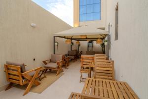 a patio with chairs and tables and an umbrella at Aurion AsSalaam Hotel Apartment in Medina