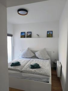 a white bedroom with a bed with two green pillows at Ferienwohnung Löwenrevier in Winningen