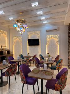 a restaurant with tables and chairs and a chandelier at GUZAL Boutique Hotel in Bukhara
