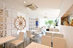 a restaurant with white chairs and tables and a large clock at Hotel nanvan浜名湖 in Kosai