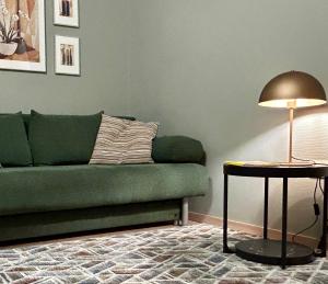 a living room with a green couch and a table with a lamp at Vita Apartmanok in Hévíz