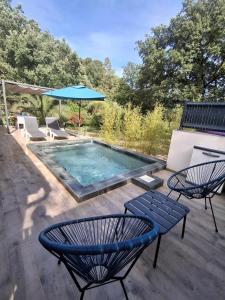a swimming pool with two chairs and a blue umbrella at La Motte in La Motte