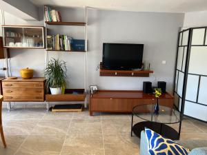 a living room with a flat screen tv on a wall at Ou Souleou appartement 3 étoiles dans villa Spa béton jardin vue mer et colline in Bormes-les-Mimosas