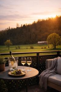 a table with two glasses of wine and a plate of food at Romantic Sunset Retread I 4 Min to A2 I E-Bikes I Near Ljubljana in Velika Loka