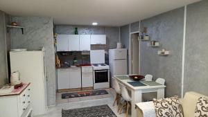 a kitchen with a white refrigerator and a table with chairs at Jela - Spacious Two-Bedroom Apartment near City Center with Free Parking & Wi-Fi in Podgorica