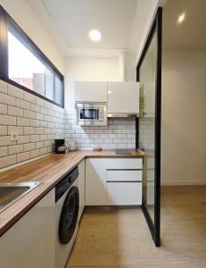 a kitchen with white cabinets and a washer and dryer at Bilbao ROOMS & KITCHEN Zabalburu in Bilbao