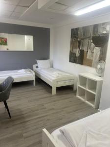 a room with two beds and a chair in it at Pension Passion Julie in Berlin