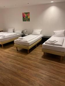 two beds in a room with wood floors at Pension Passion Julie in Berlin
