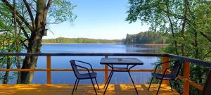 a table and two chairs on a deck overlooking a lake at BEJOT domki nad jeziorem in Wysoki Most