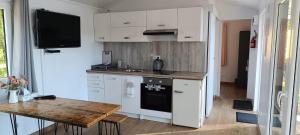 a kitchen with white cabinets and a wooden table at BEJOT domki nad jeziorem in Wysoki Most