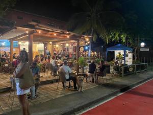 a group of people sitting outside of a restaurant with a dog at Conforto e Paz in Imbassai