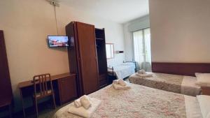a bedroom with two beds and a cabinet with a tv at Hotel Villa Verde in San Mauro a Mare