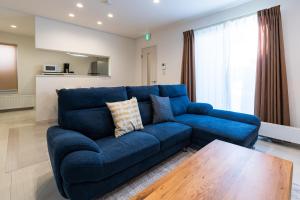 a blue couch in a living room with a table at Nomad Stay Chitose in Chitose