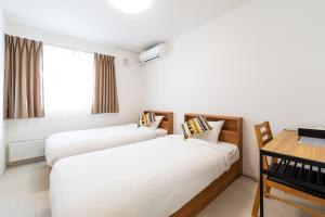 a hotel room with two beds and a table at Nomad Stay Chitose in Chitose