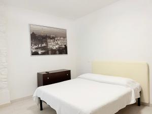a white bedroom with a bed and a picture on the wall at CasaMare - Numana, comodo trilocale in centro in Numana