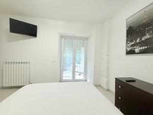 a white bedroom with a large bed and a window at CasaMare - Numana, comodo trilocale in centro in Numana