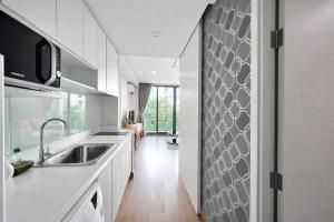 a kitchen with white cabinets and a sink and a hallway at 1Bedroom+Sofa bed, Luxury Condo@Nimmana in Chiang Mai