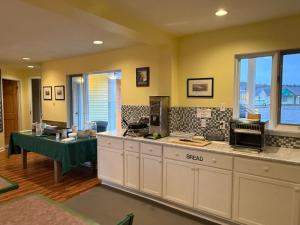 a kitchen with white cabinets and a green table at Annapolis Royal Inn & Suites in Annapolis Royal