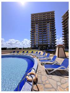 a pool with lounge chairs and two tall buildings at Tulivu Beach Stays in Jeuri