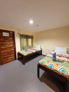a room with two beds and a door at Rain Haven Lodging House in Coron