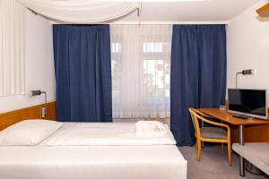 a bedroom with a bed and a desk with a computer at Vlachos Hotel in Delitzsch