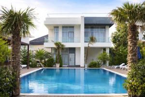 a villa with a swimming pool and palm trees at Lanai Villas Beach Side in Baku