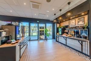 a large room with a counter and a restaurant at B&B HOTEL Landerneau Bois Noir in Landerneau