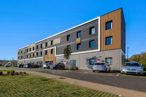 a building with cars parked in a parking lot at B&B HOTEL Landerneau Bois Noir in Landerneau