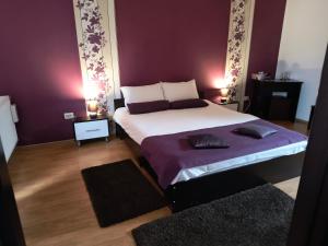a bedroom with a large bed with purple walls at Casa Mais Brașov Guesthouse with Free Parking in Braşov
