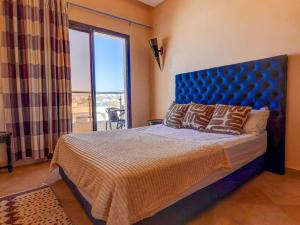 a bedroom with a bed with a blue headboard and a window at Beach Apartment with Pool Banana Beach Surf Spot in Aourir +26 photos