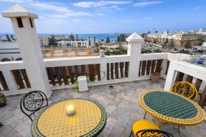 a balcony with tables and chairs and a view of the ocean at Riad Chama in Essaouira