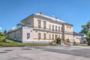 ein großes weißes Gebäude mit roten Fenstern an einer Straße in der Unterkunft Hotel Dakol in Petrovice u Karviné