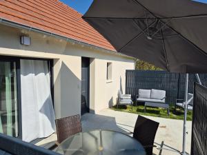 a patio with an umbrella and a table and chairs at Le cocoon idyllique in Faverolles-sur-Cher