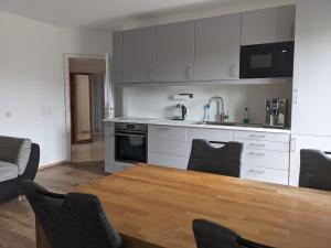 a kitchen with white cabinets and a wooden table with chairs at Ferienwohnung Lang in Nittenau