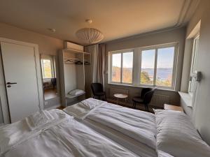a bedroom with a bed and two chairs and two windows at Åh Stifts- & Konferensgård in Ljungskile