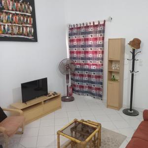 a living room with a couch and a television at Appartement Keur Diam Saly in Saly Portudal +8 photos